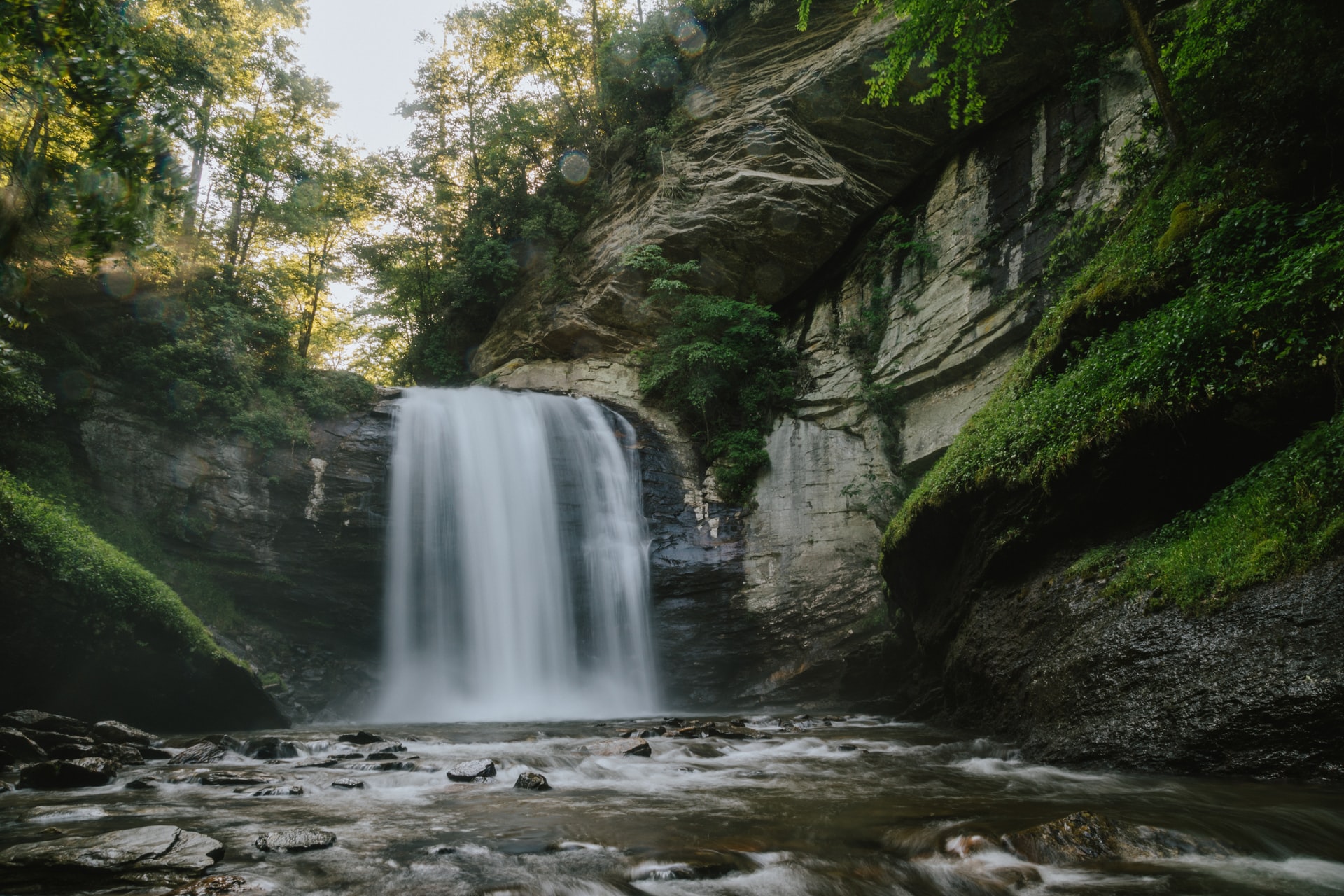 A small waterfall surrounded by moss covered rocks and cliffs.